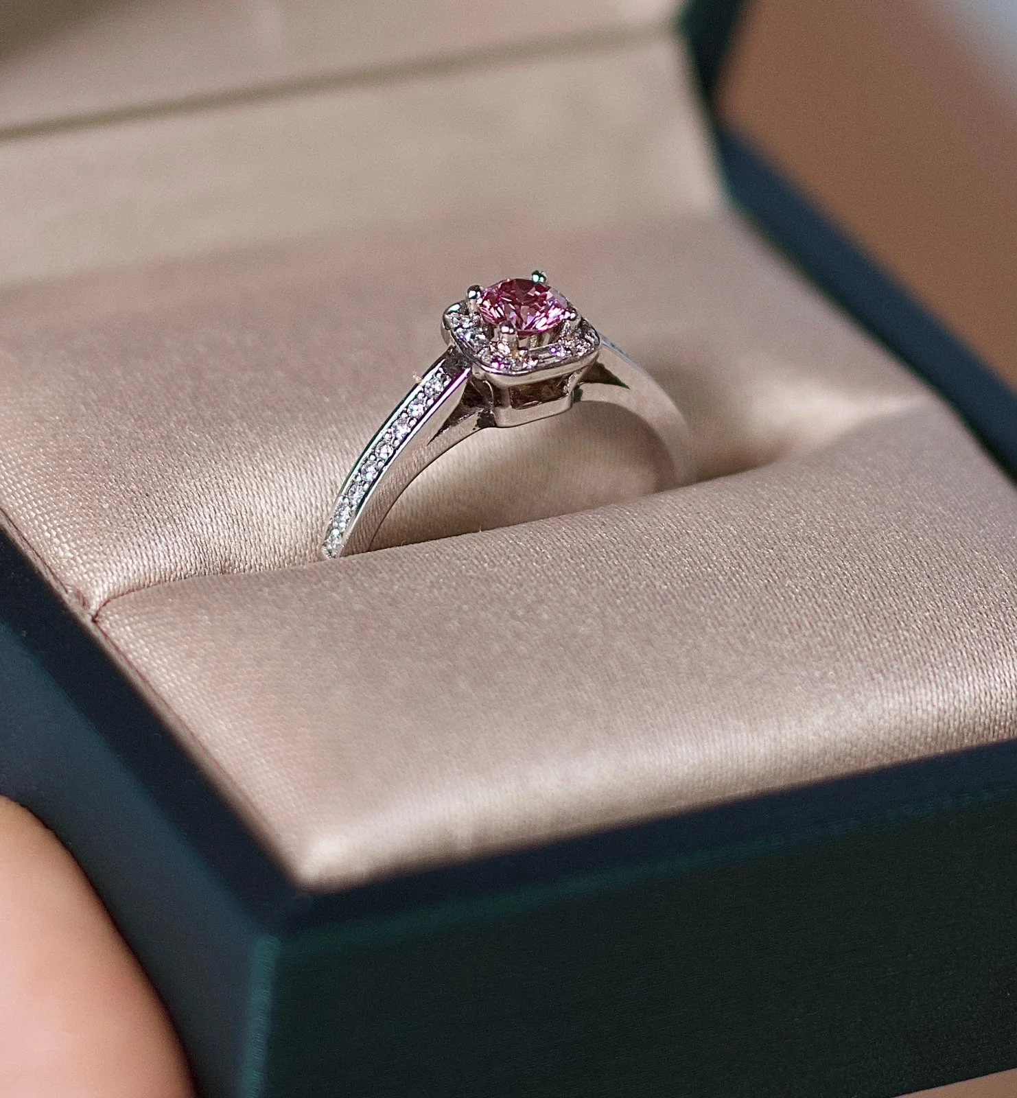 Anel solitário autoral em ouro branco 18k com diamante rosa central e cravação halo em estojo.